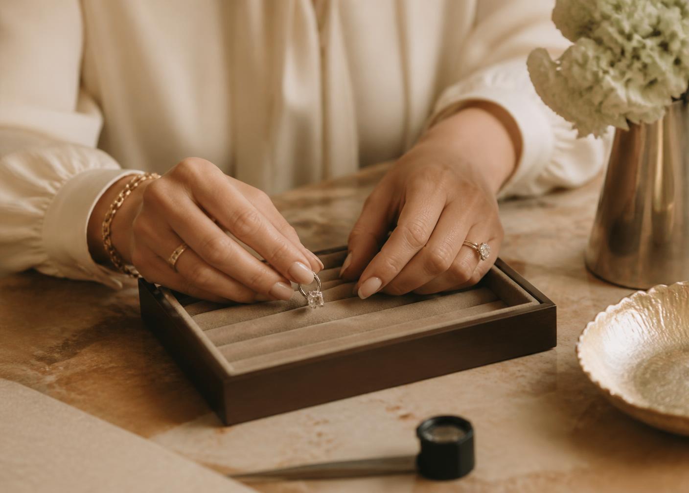 Hands placing a diamond ring into a velvet tray during a private evaluation
